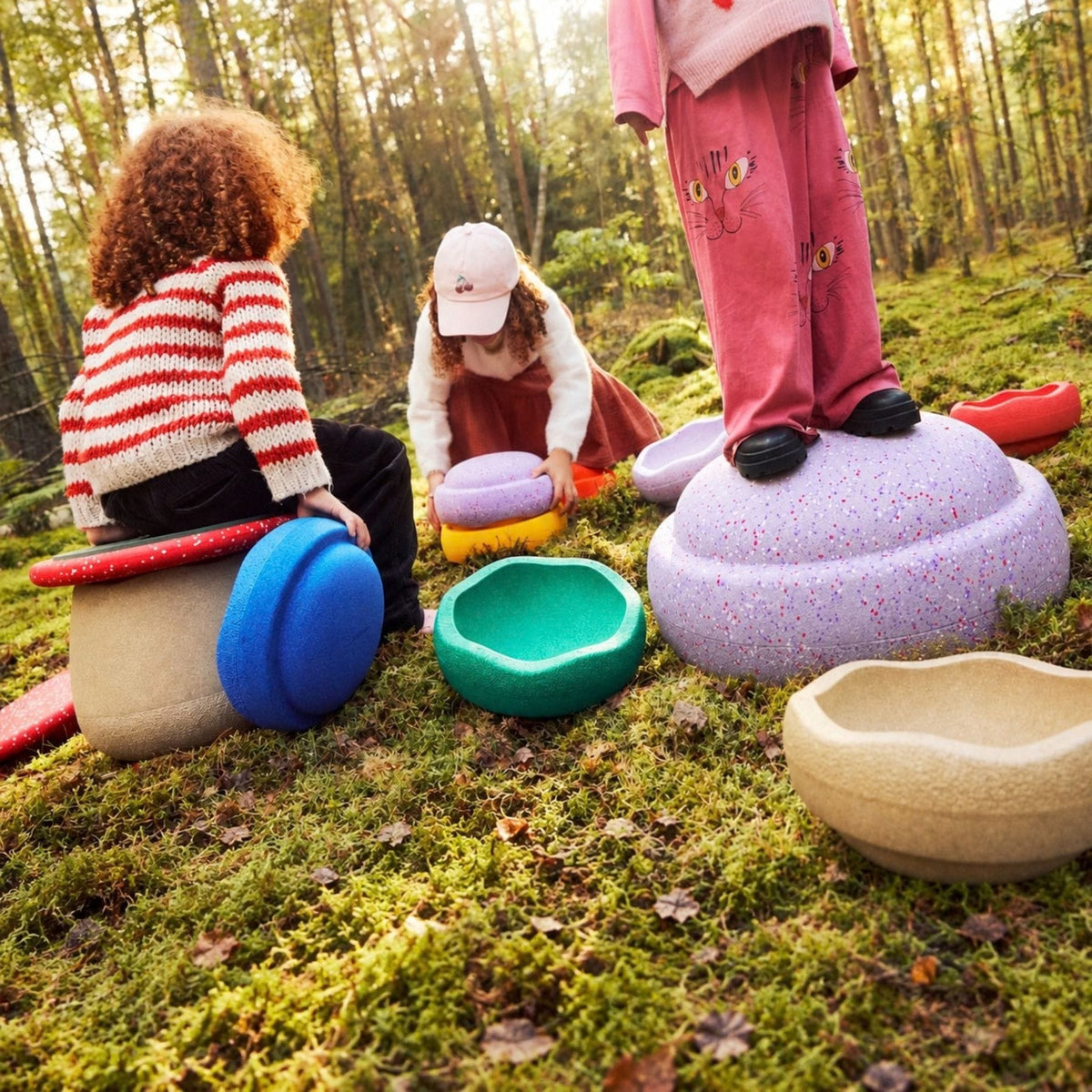 Kinder spielen im Wald mit mehreren Grow-Steinen und bunten Schalen zwischen den Bäumen